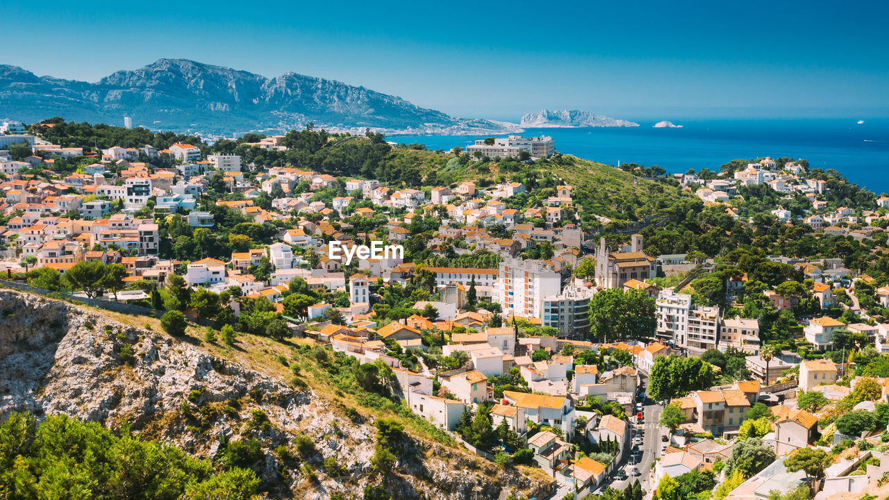 high angle view of townscape by sea against blue sky