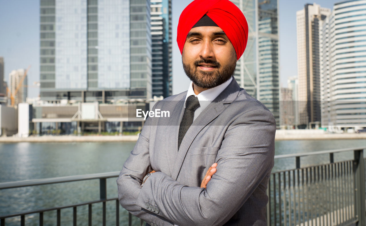 Portrait of businessman wearing turban standing against river