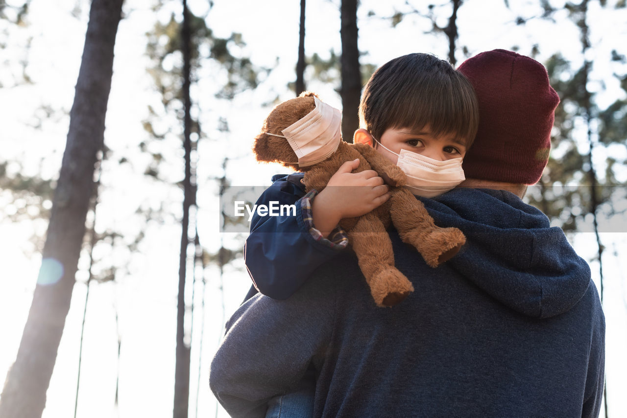 PORTRAIT OF BOY HOLDING ICE CREAM STANDING AGAINST TREES