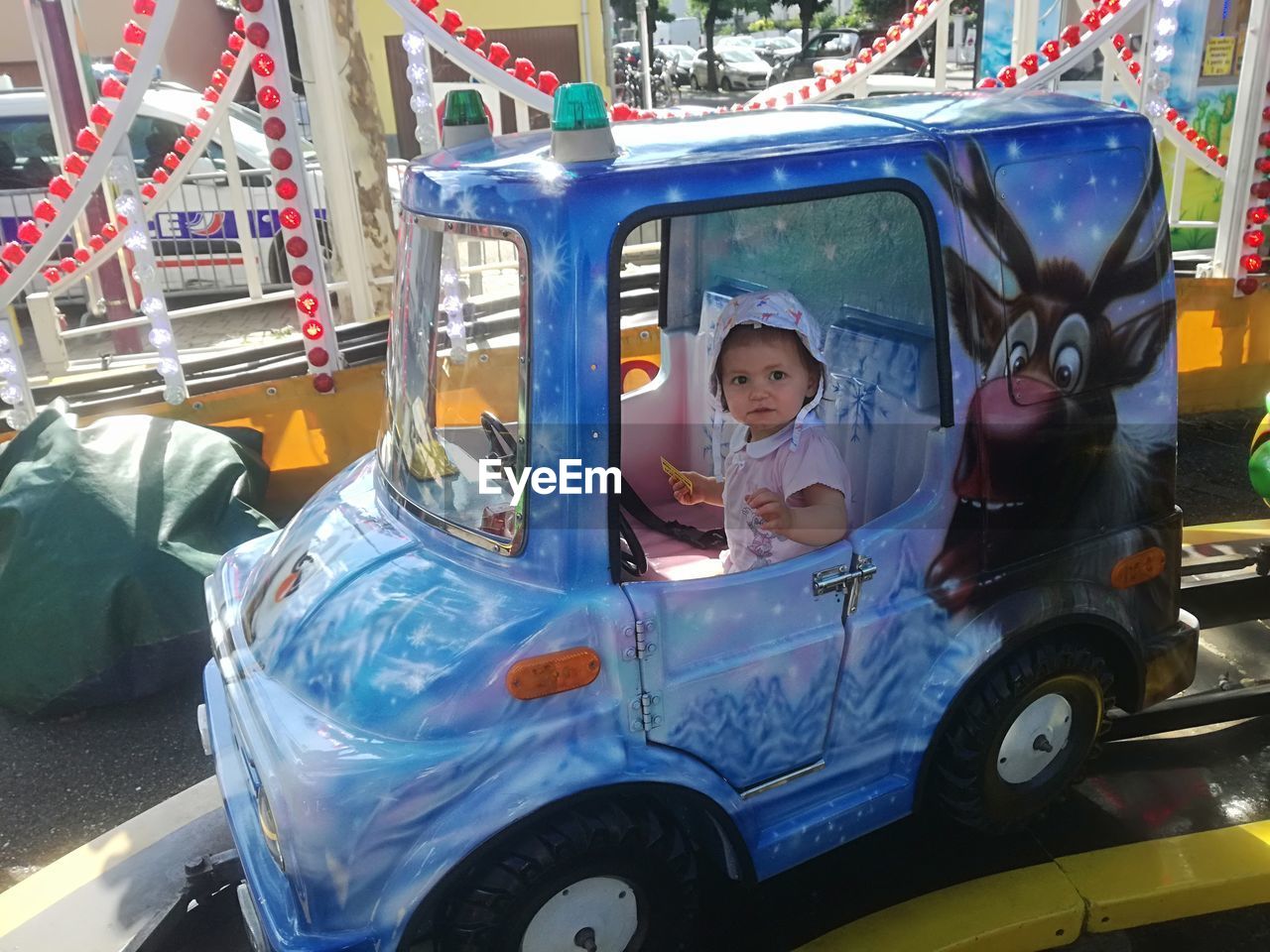 Portrait of cute baby girl sitting in toy car