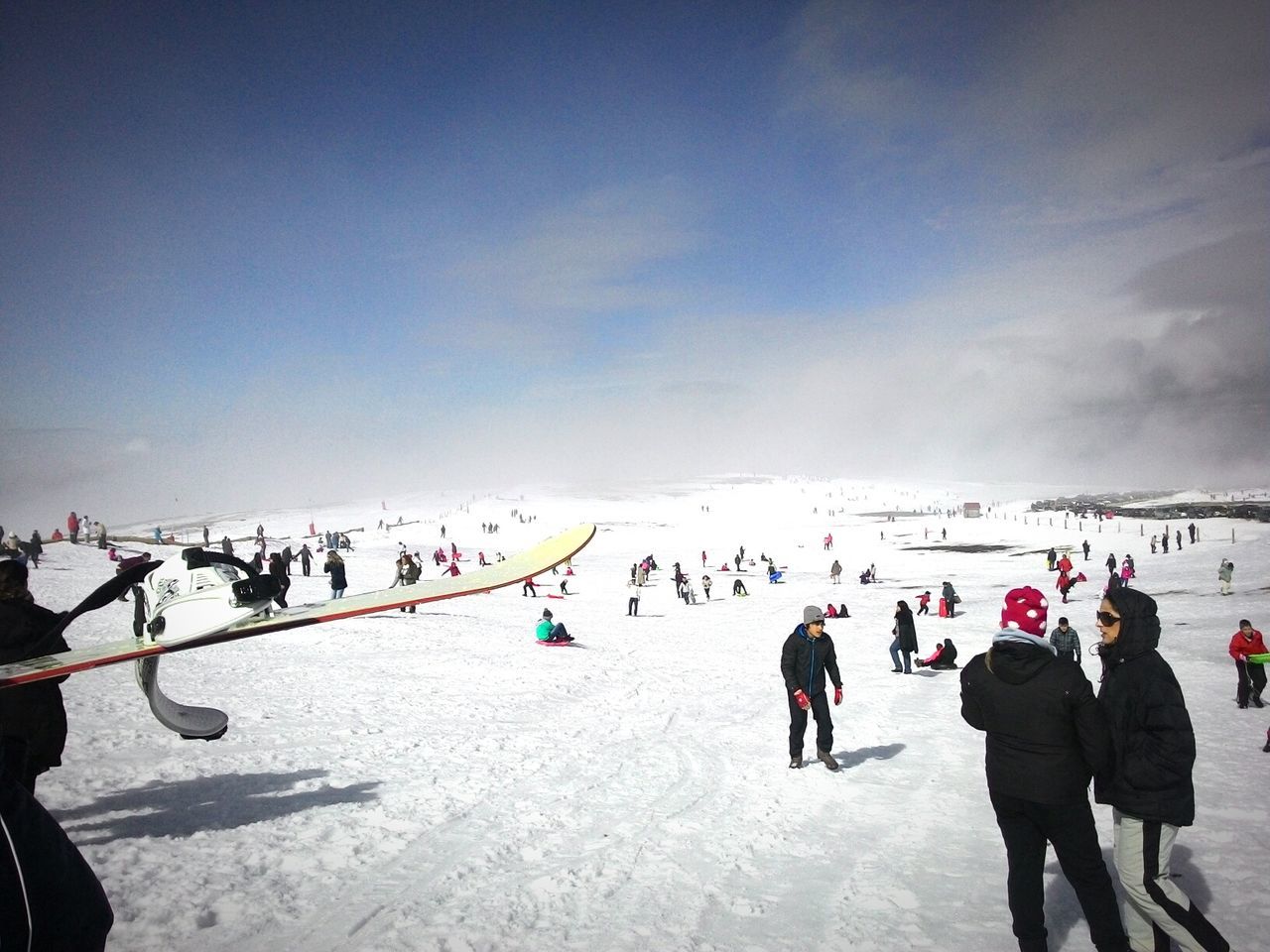 People enjoying on snow covered mountain against sky