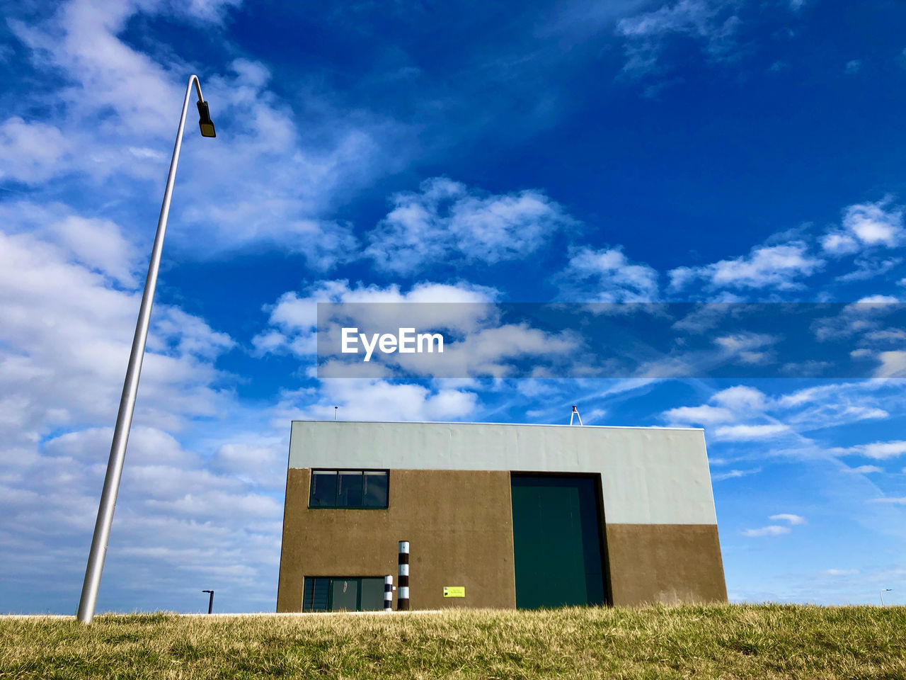 LOW ANGLE VIEW OF BUILDING ON FIELD AGAINST BLUE SKY