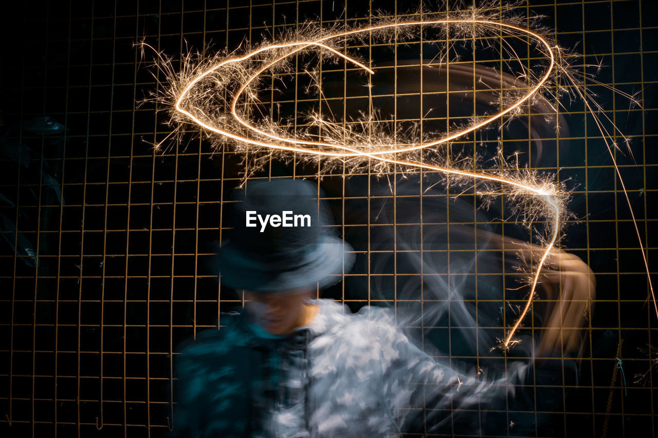 Blurred motion of man making trails with illuminated sparkler