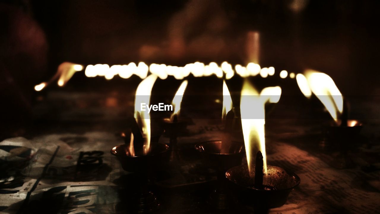 CLOSE-UP OF ILLUMINATED BURNING CANDLES