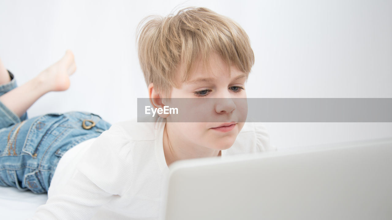 PORTRAIT OF BOY USING SMART PHONE IN LAPTOP