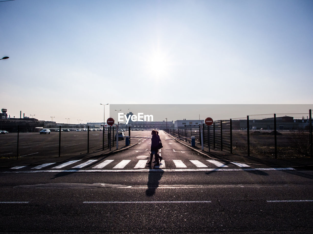 People walking on zebra crossing against clear sky