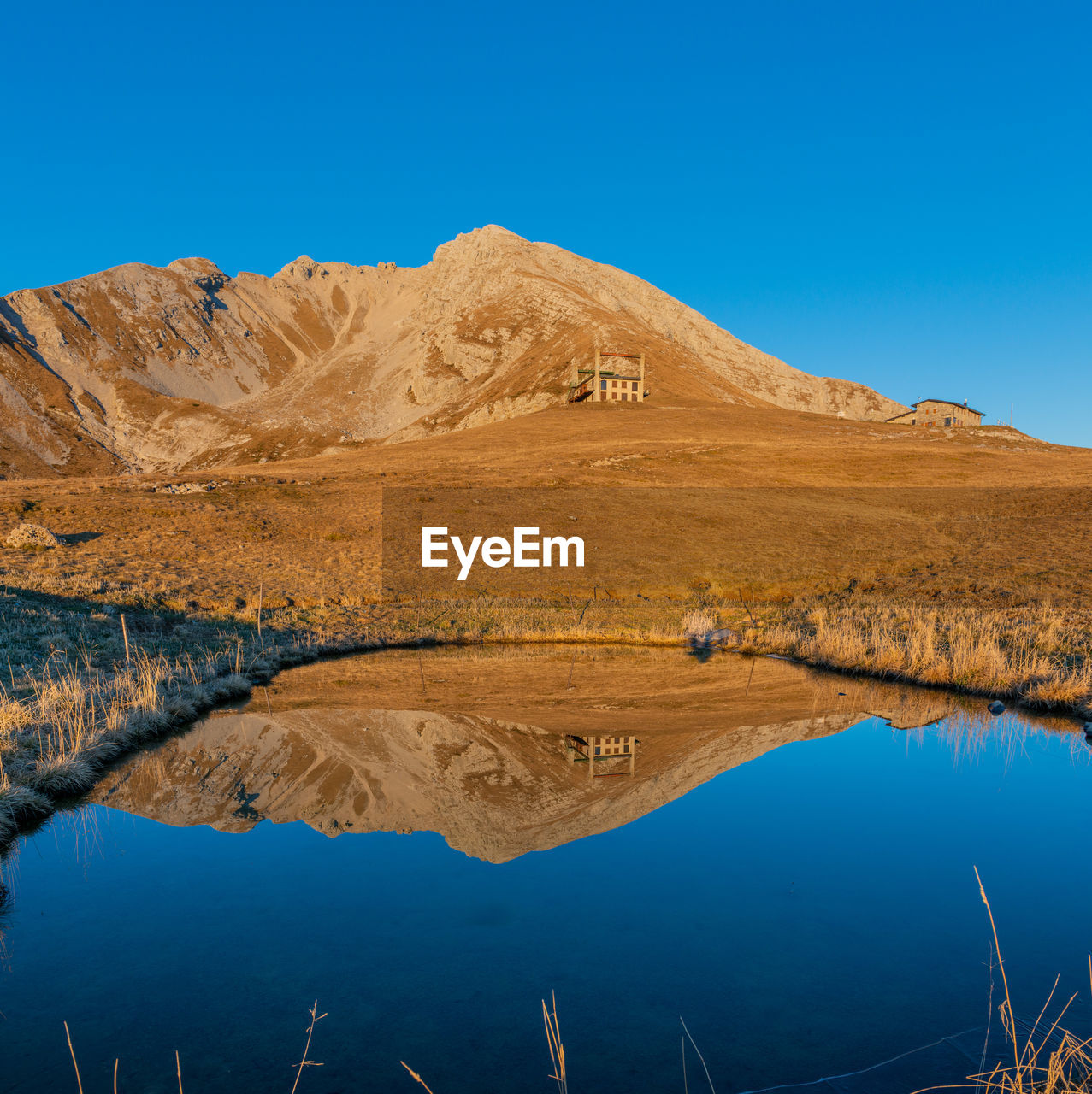 Scenic view of lake and mountains against clear blue sky