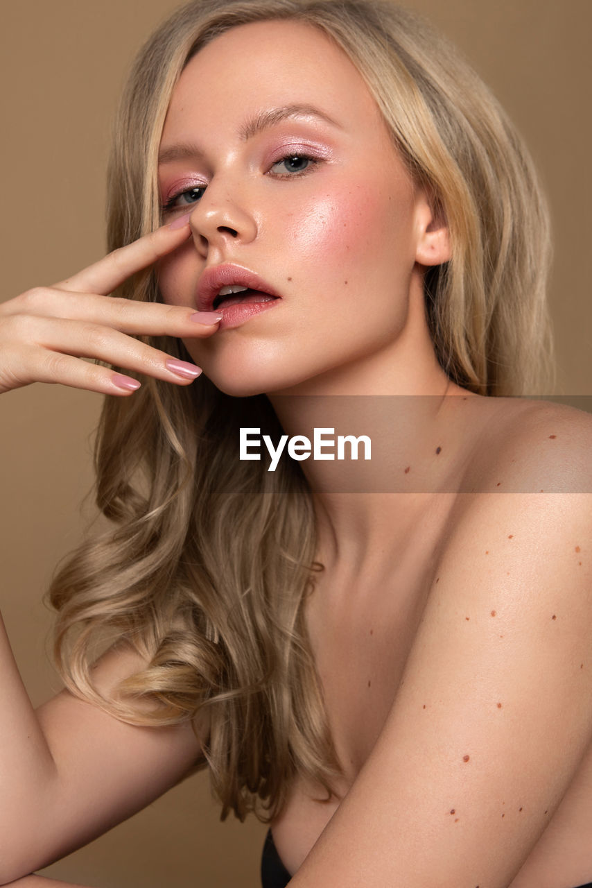 Close-up of beautiful young woman against colored background