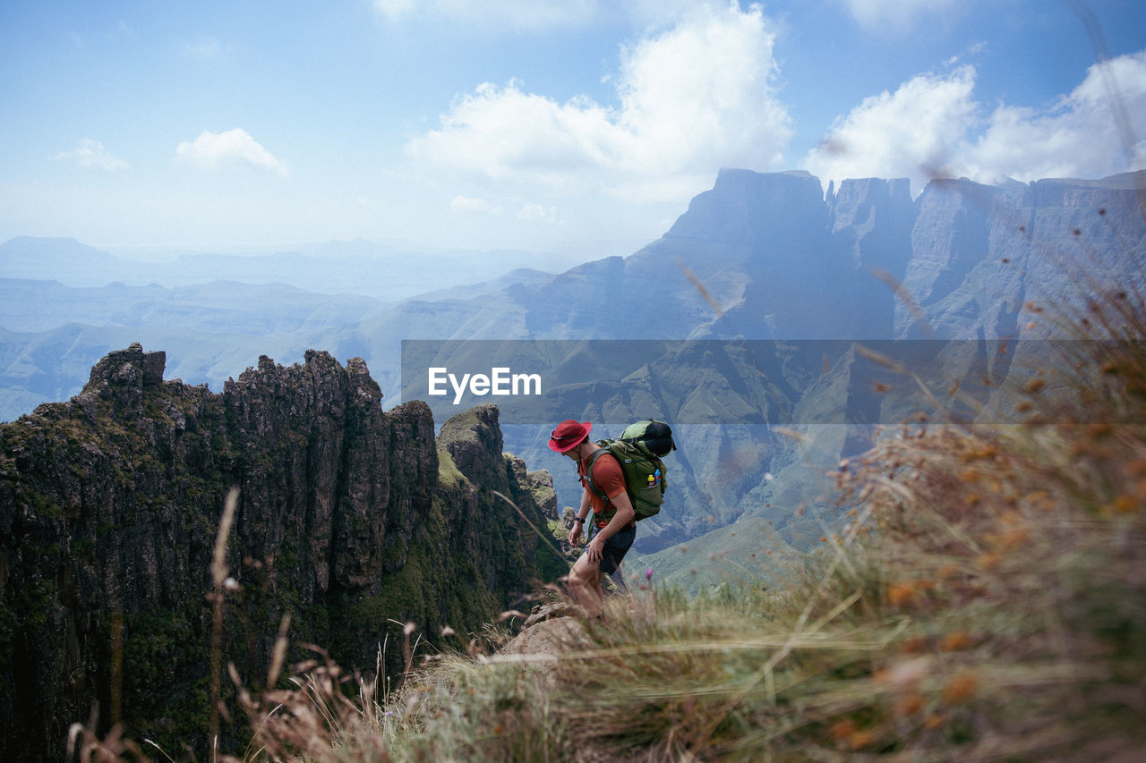 Rear view of man standing on mountain against sky