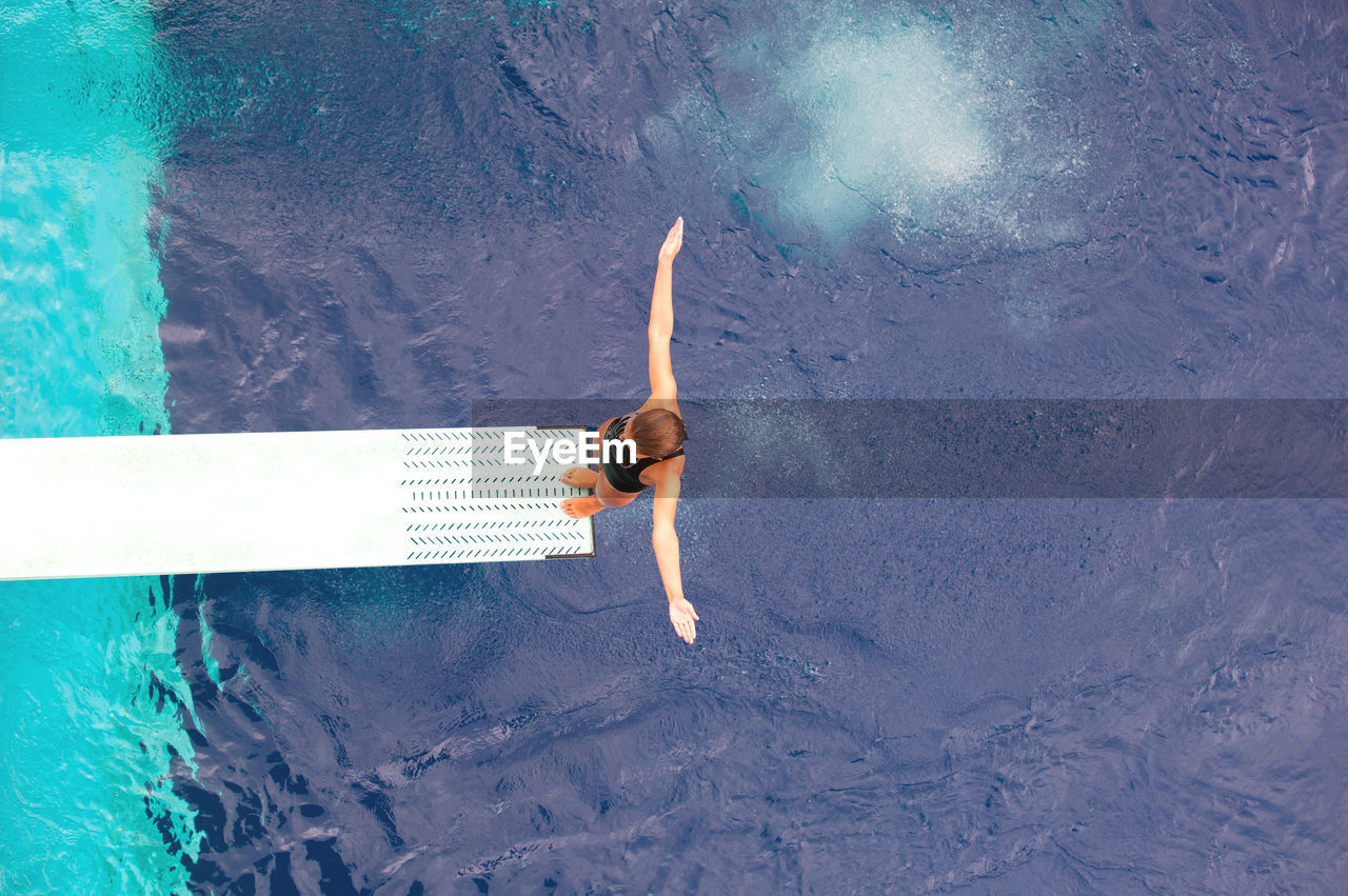 HIGH ANGLE VIEW OF WOMAN SWIMMING IN SEA