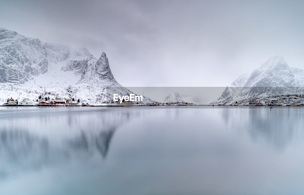 Scenic view of lake by snowcapped mountains against sky