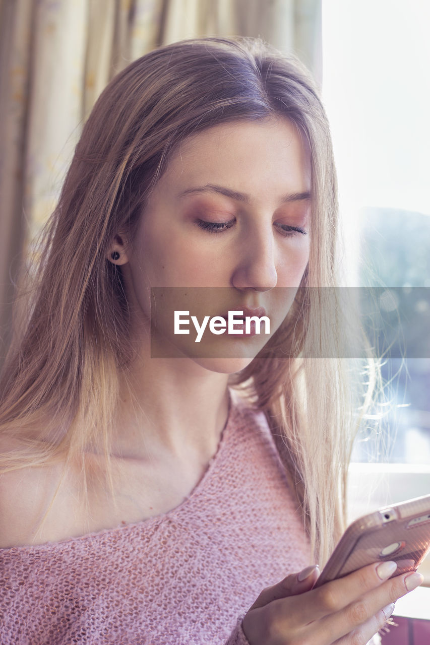 Blonde woman texting, browsing the internet