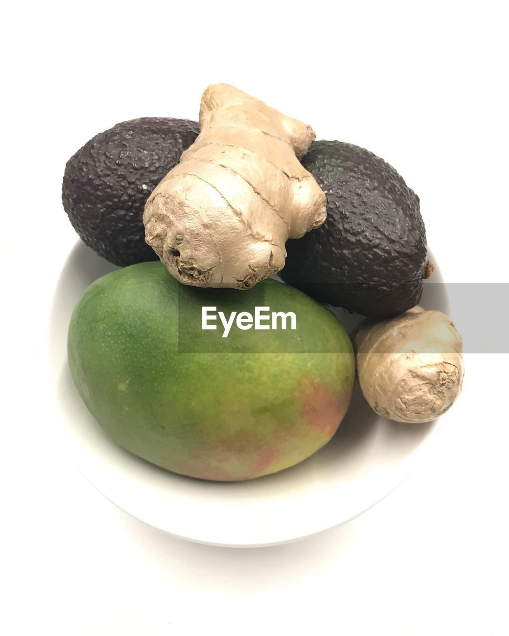 High angle view of mango fruit, avocado vegetable and ginger root on white table background