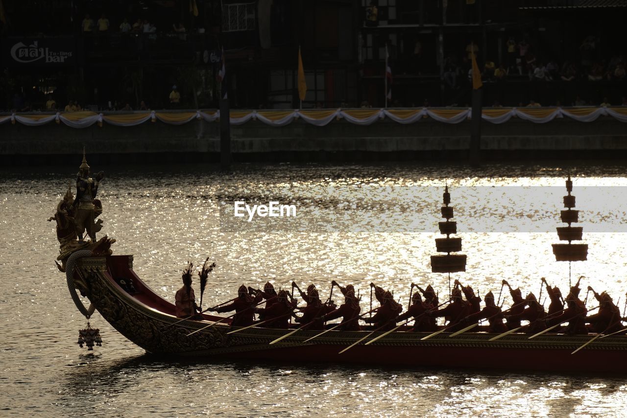 People on boat in river against built structures