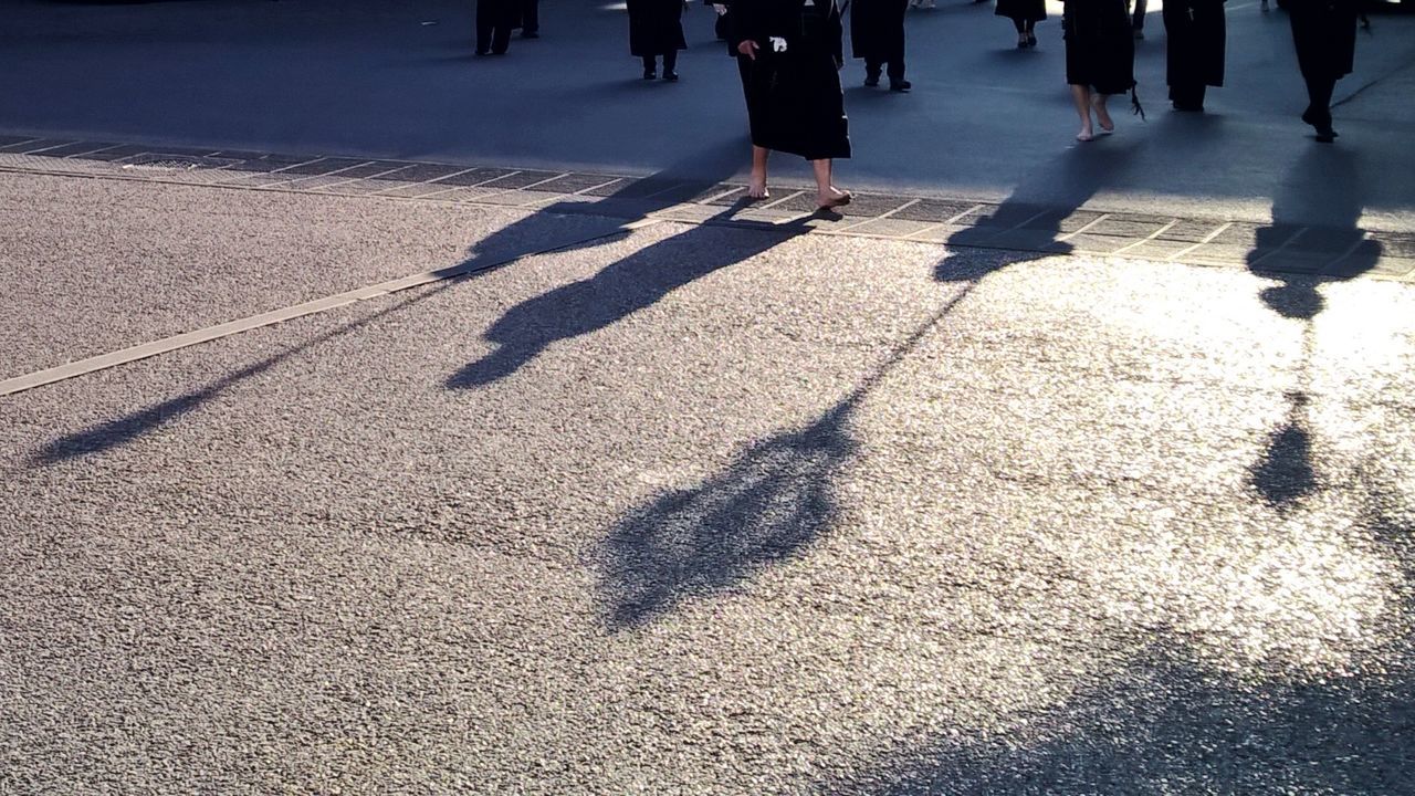 LOW SECTION OF PEOPLE WITH SHADOW ON STREET