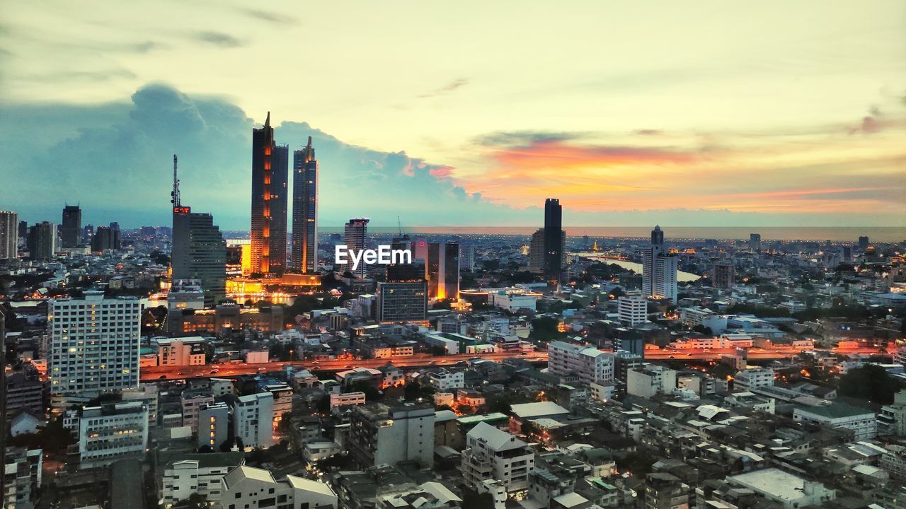 AERIAL VIEW OF BUILDINGS AGAINST CLOUDY SKY