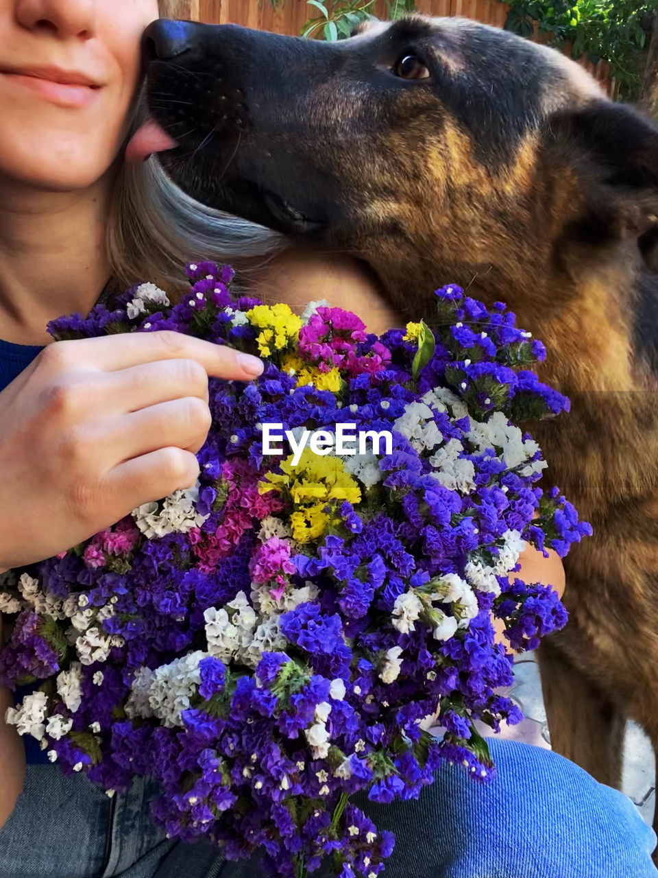 mammal, animal themes, animal, flower, domestic animals, one animal, flowering plant, one person, pet, plant, women, adult, nature, person, leisure activity, lifestyles, canine, dog, clothing, young adult, holding, smiling, day, female, happiness, human face, close-up, outdoors, beauty in nature, positive emotion, emotion, freshness, casual clothing, portrait, love, friendship