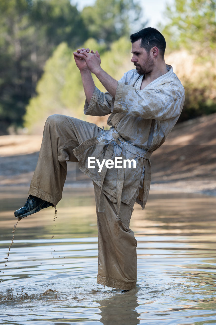 Man kicking in lake against trees