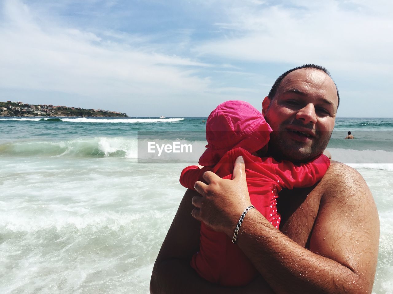 Portrait of smiling father holding daughter at beach on sunny day