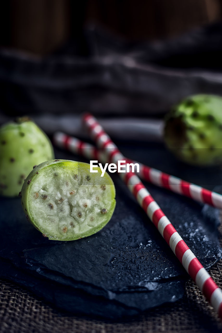 Close-up of fruits with drinking straw on slate