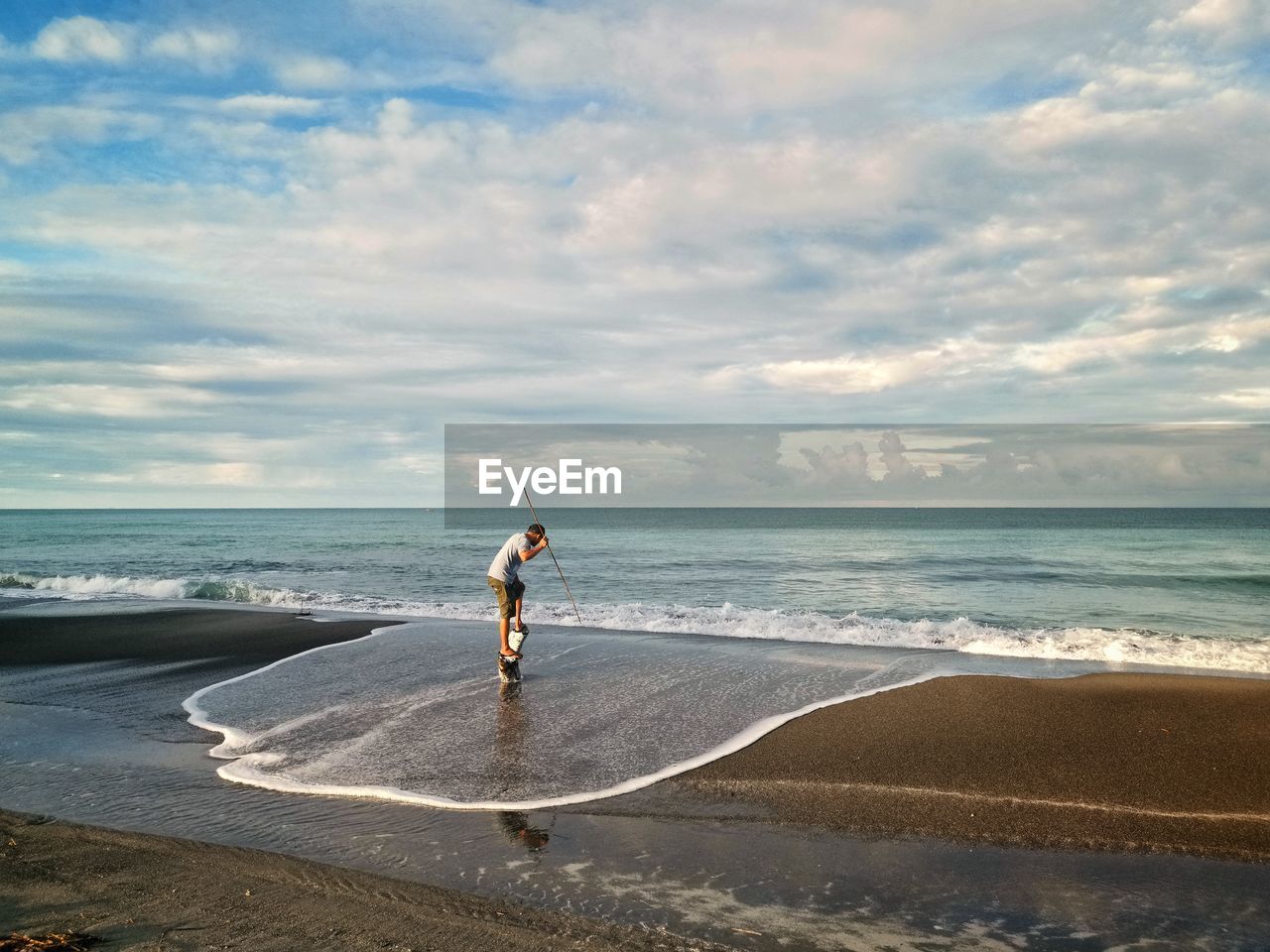 BOY ON BEACH AGAINST SKY