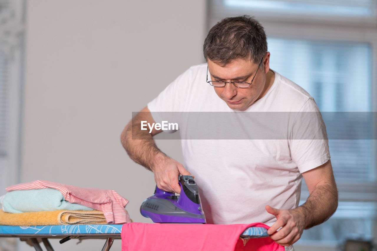 Man ironing cloth at home