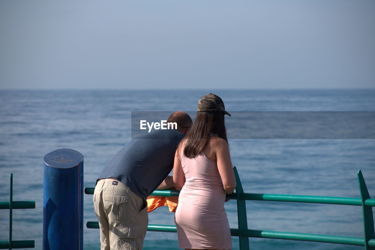 Rear view of couple looking at sea against clear sky