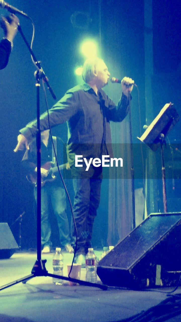 MAN HOLDING UMBRELLA WHILE STANDING AT CONCERT