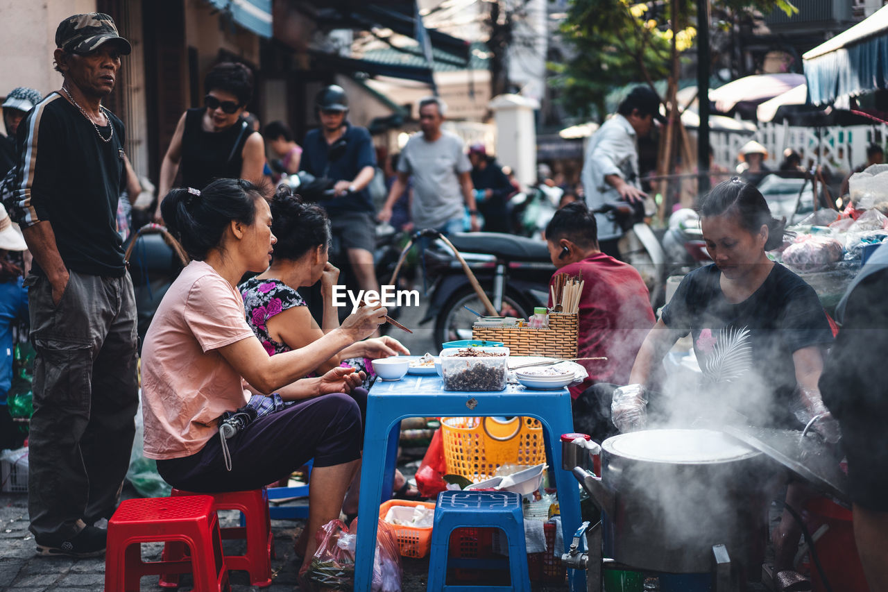 GROUP OF PEOPLE AT MARKET STALL