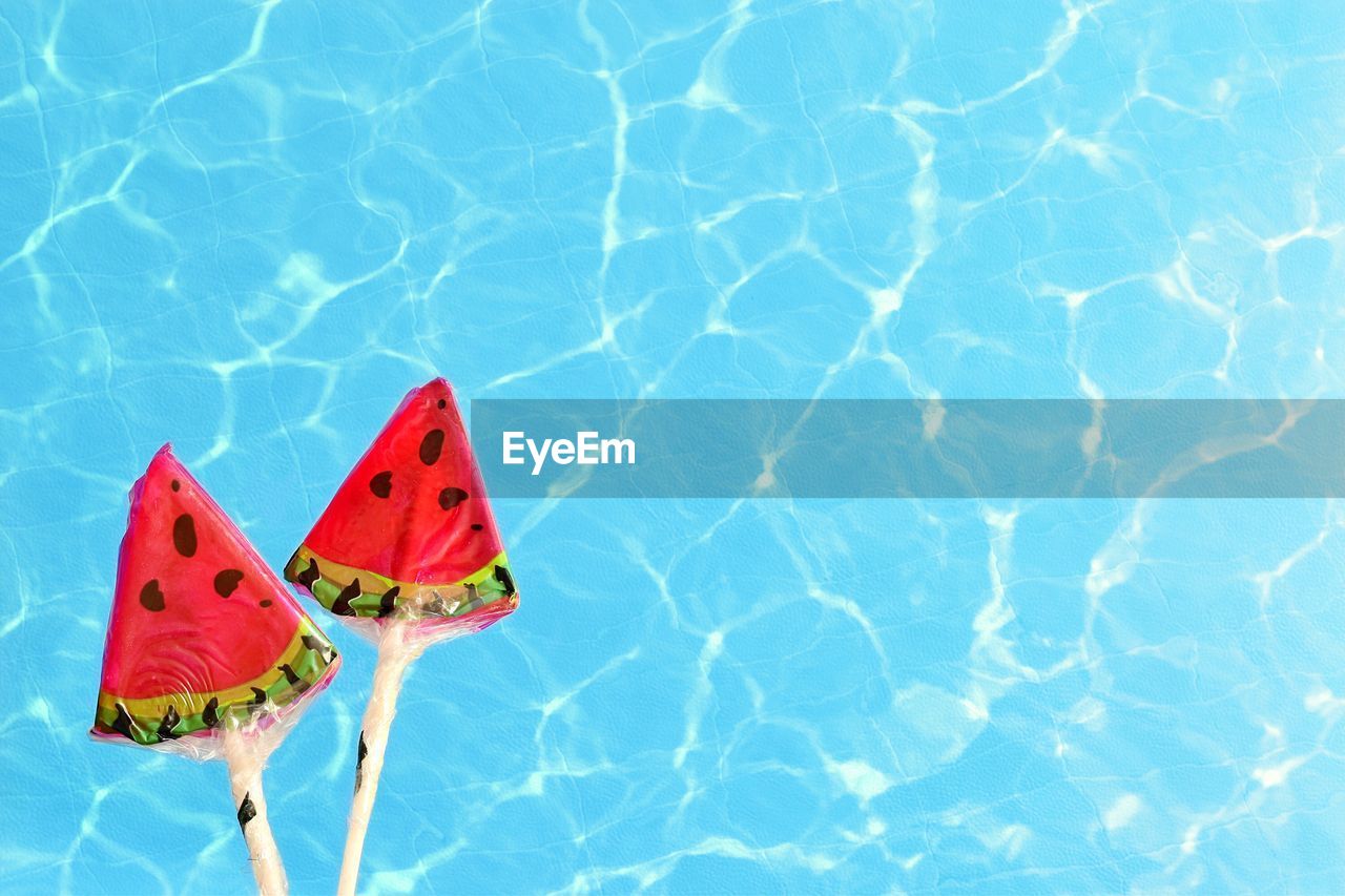 Directly above shot of watermelon lollipop over swimming pool