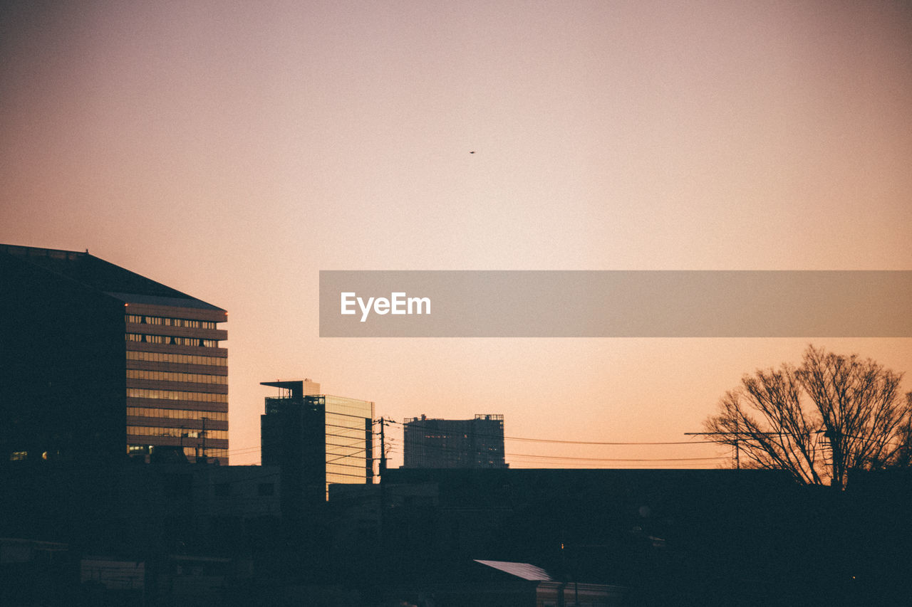 Silhouette of buildings against clear sky at sunset