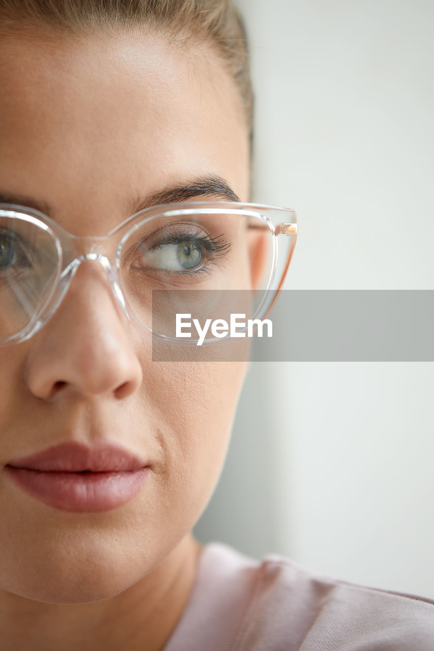 close-up portrait of young woman wearing eyeglasses against white background