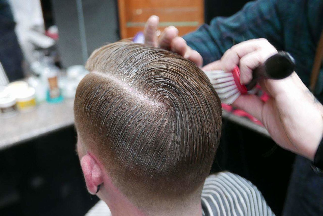 Cropped hands of barber adjusting man hair