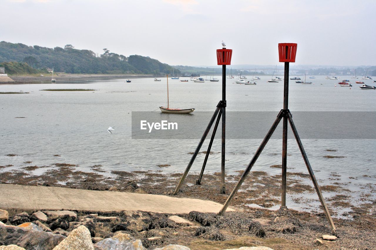 Tripods at beach against sky