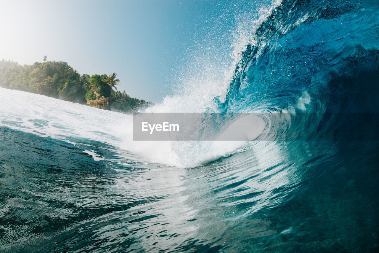 Waves splashing in sea against clear sky