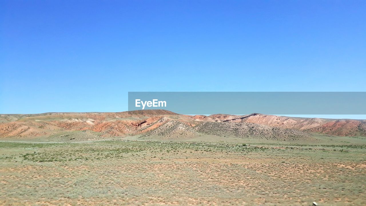 SCENIC VIEW OF ARID LANDSCAPE AGAINST BLUE SKY