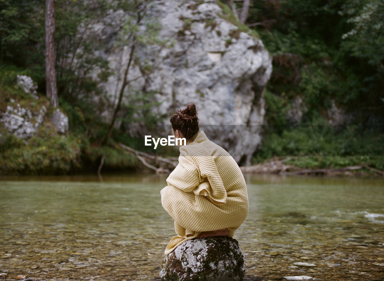 REAR VIEW OF WOMAN STANDING ON ROCK