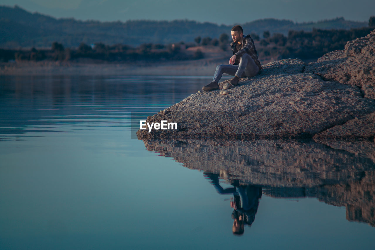 Woman sitting on rock at lake