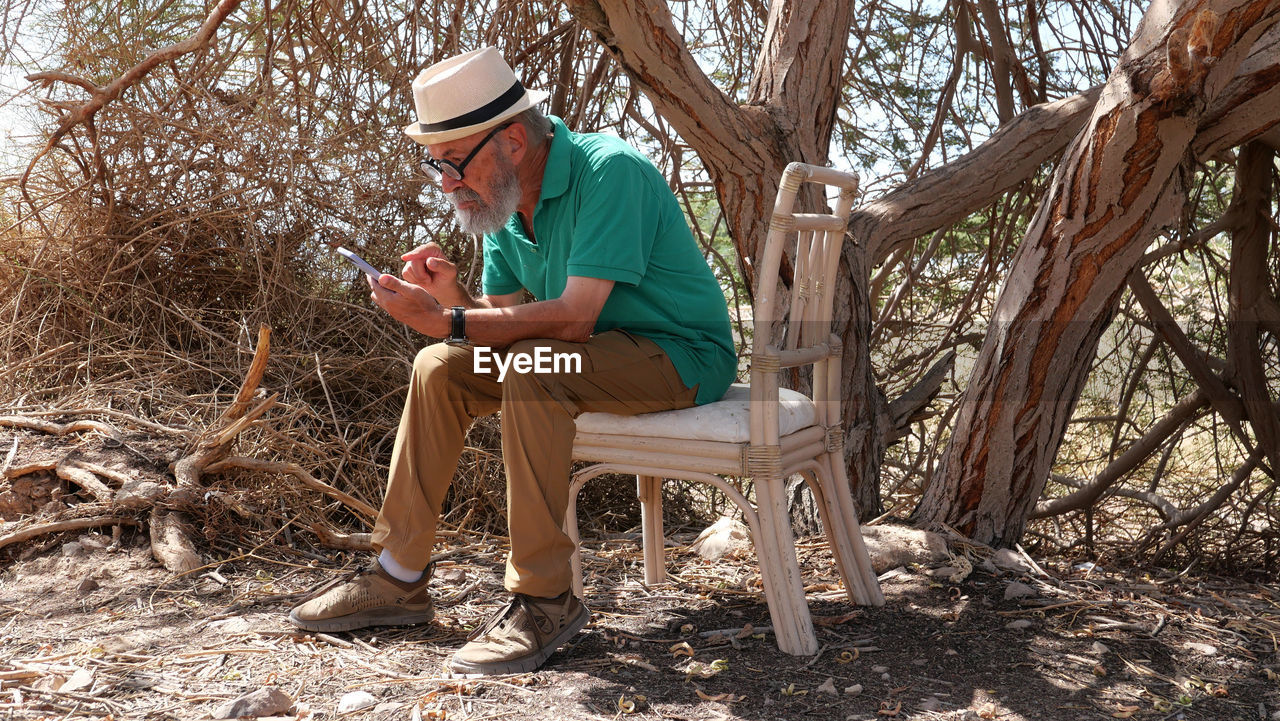 Senior man using smart phone in the desert 