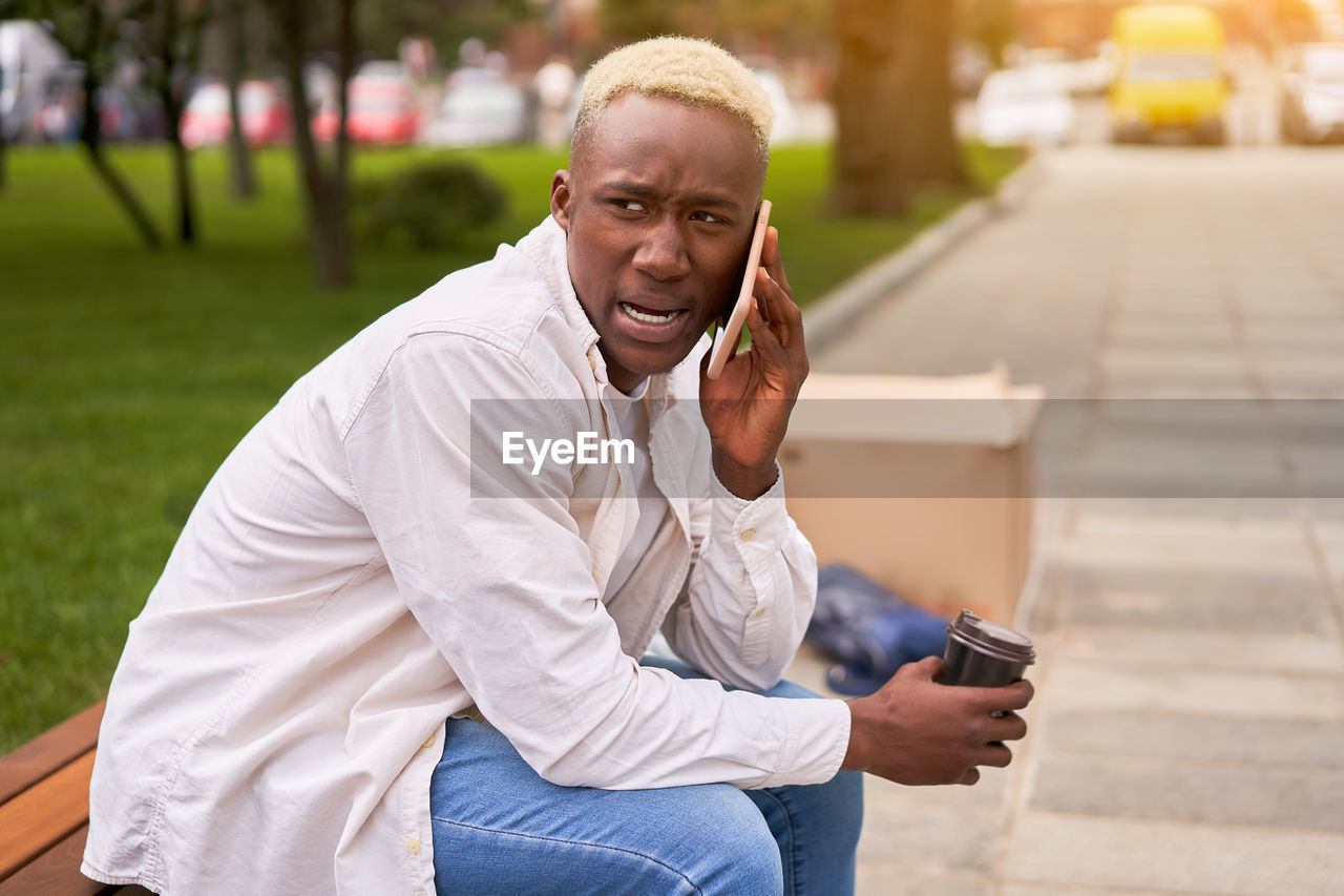 Young man talking on phone while sitting at park