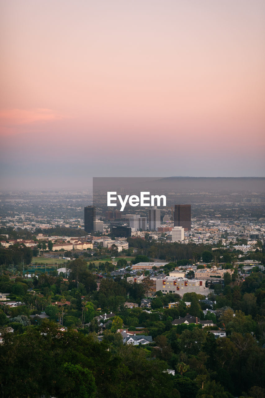 HIGH ANGLE VIEW OF BUILDINGS IN CITY AGAINST SKY DURING SUNSET