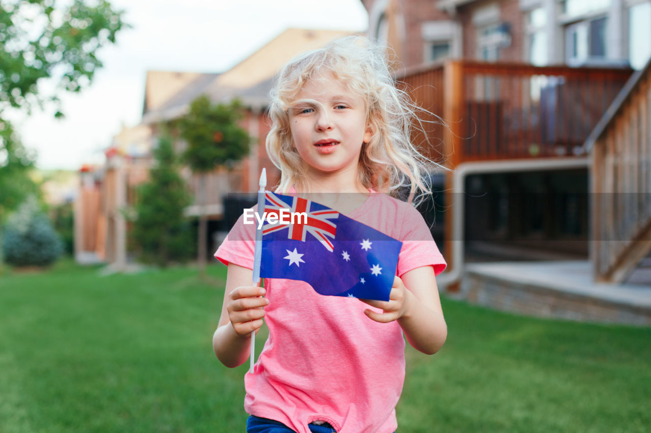 Cute girl holding australian flag at lawn