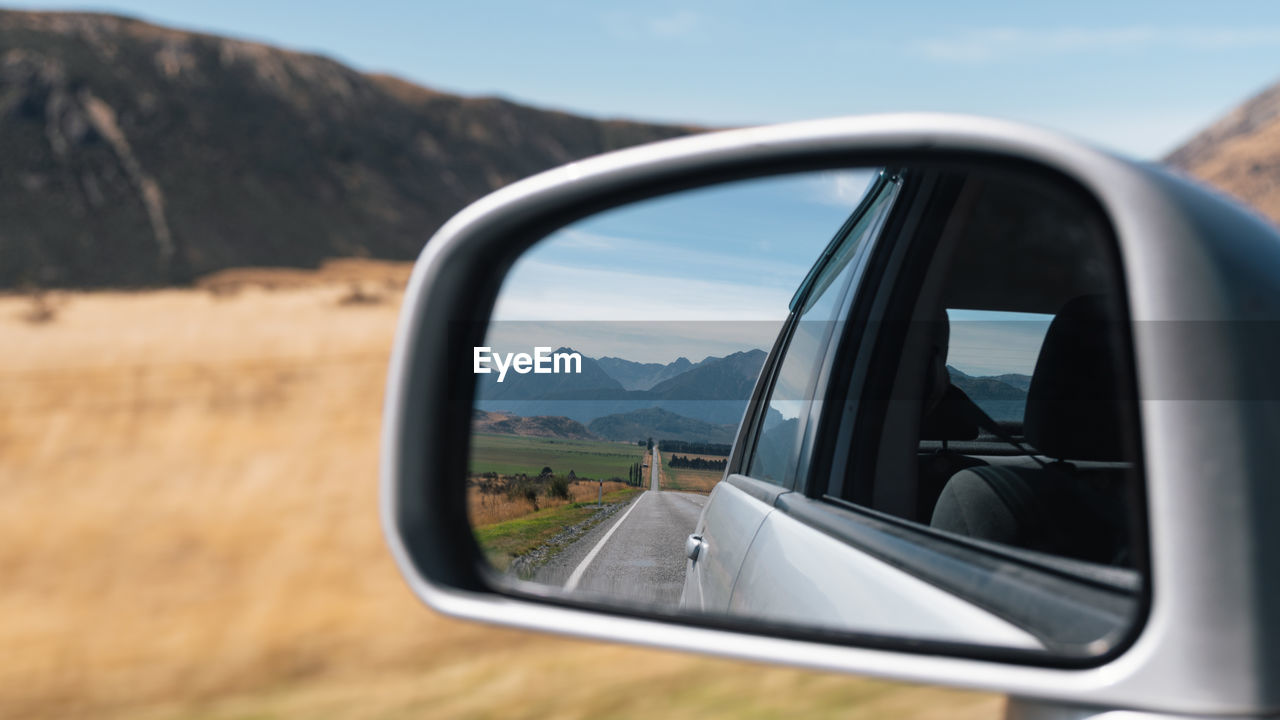 REFLECTION OF SIDE-VIEW MIRROR OF CAR ON ROAD