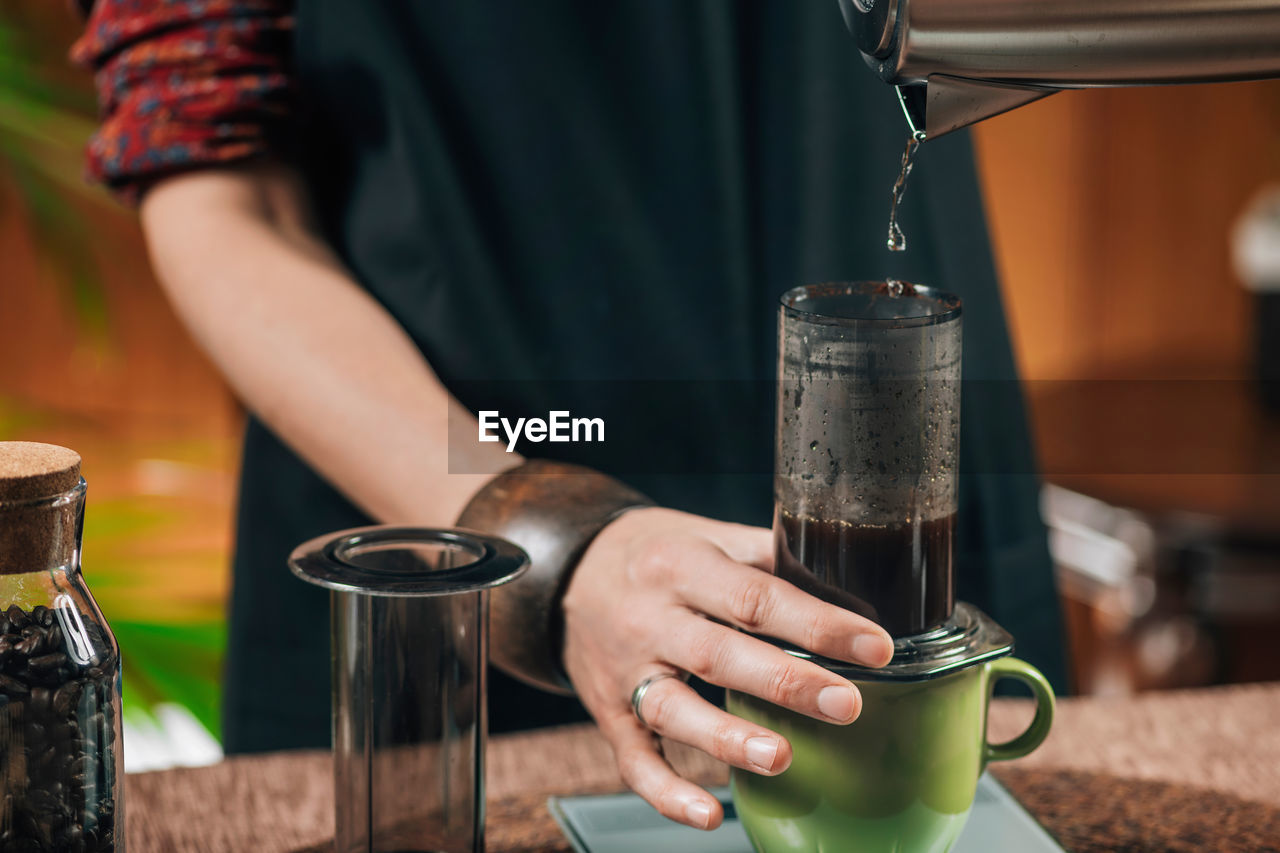 Midsection of woman making coffee in cafe