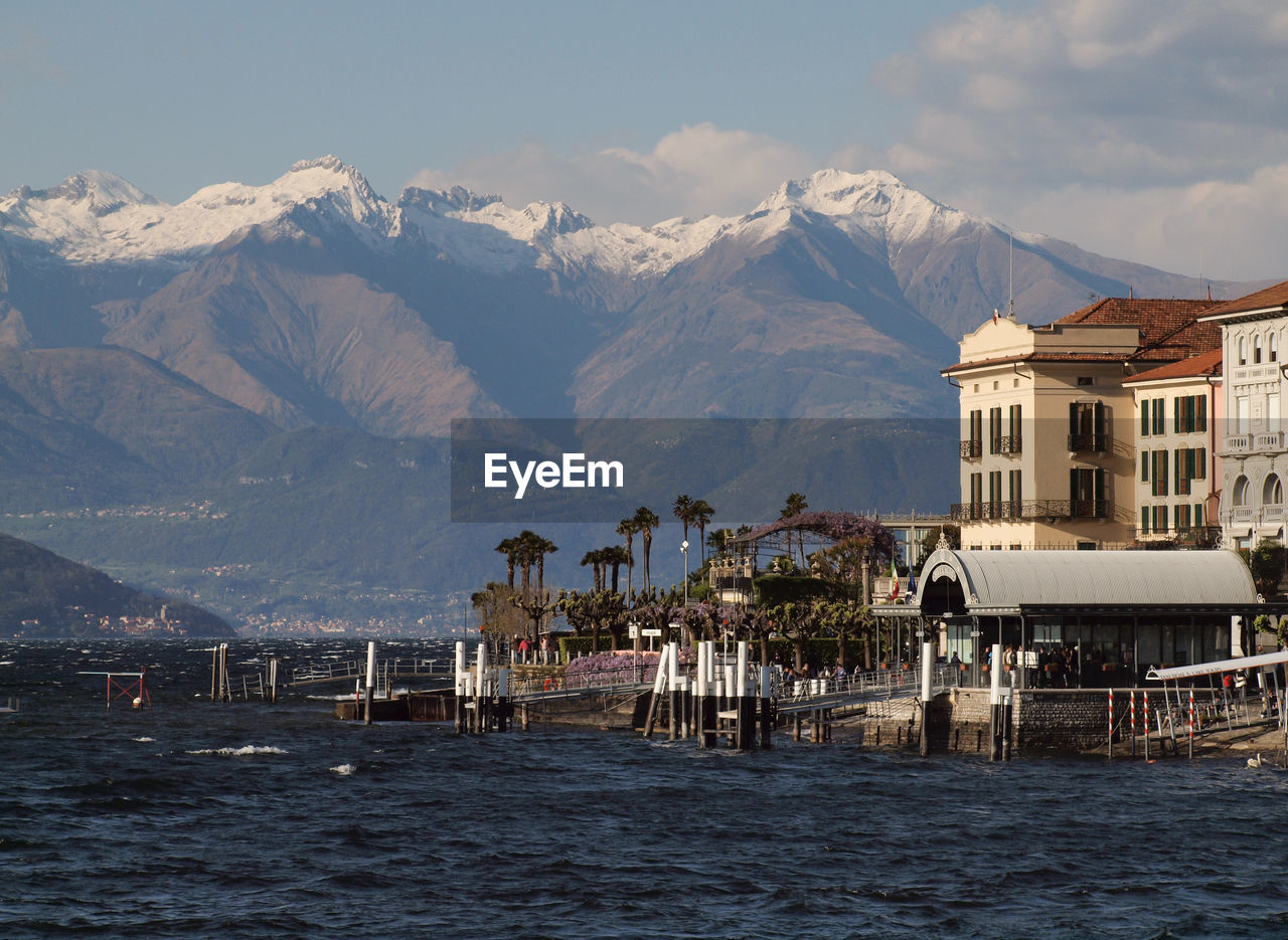 Scenic view of sea by buildings and mountains against sky