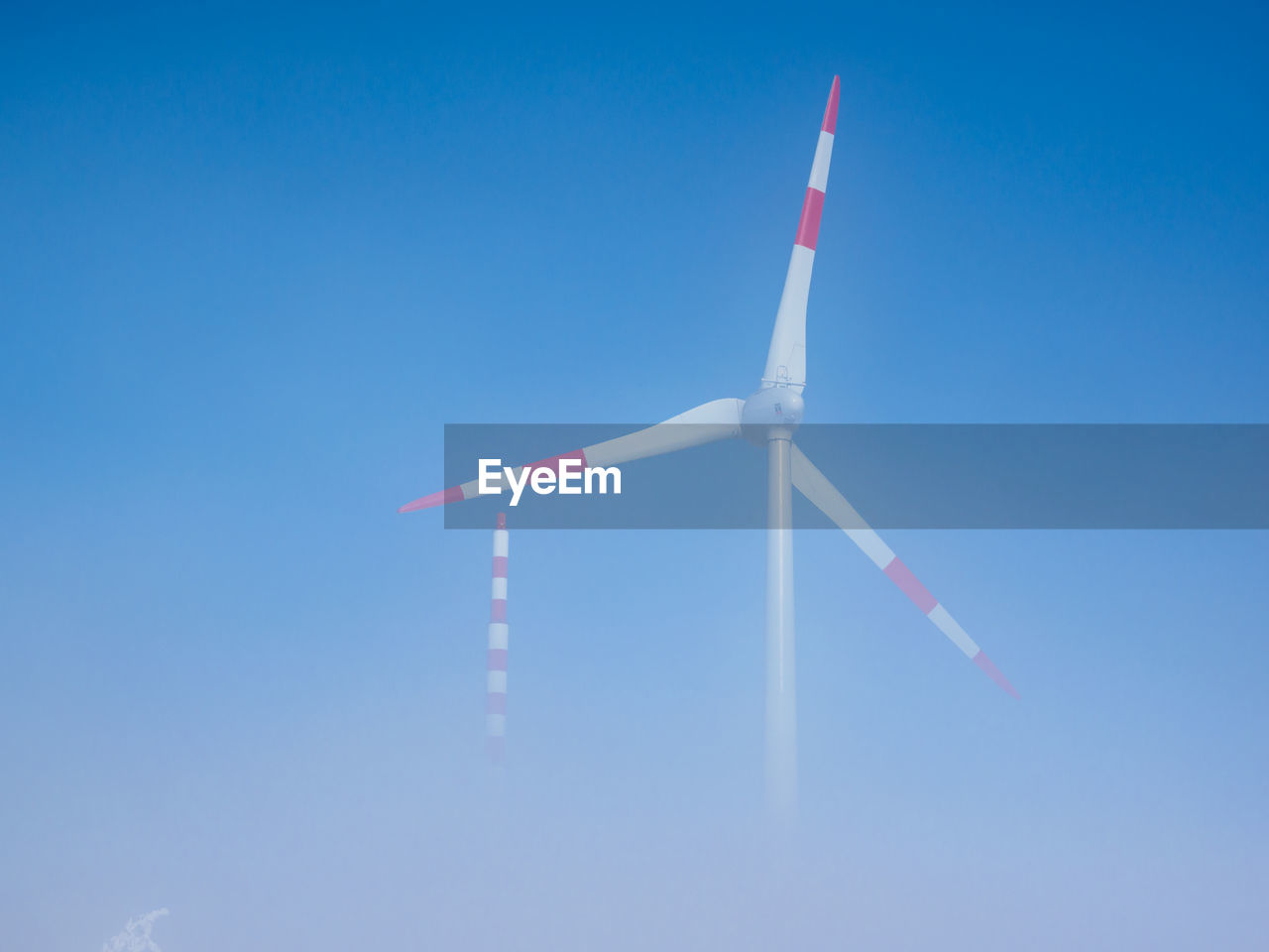 Low angle view of windmill against clear blue sky