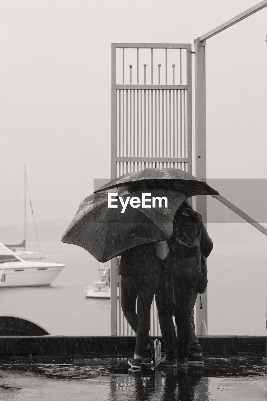 MAN STANDING ON WET SHORE AGAINST SEA