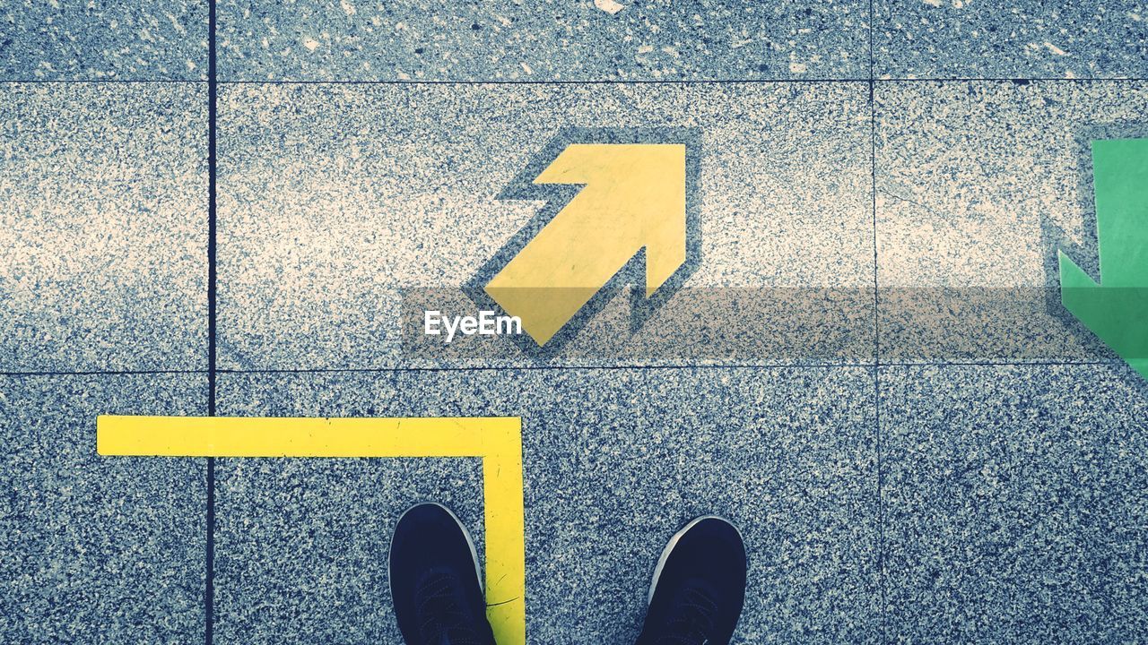 High angle view of shoes on tile floor by arrow sign