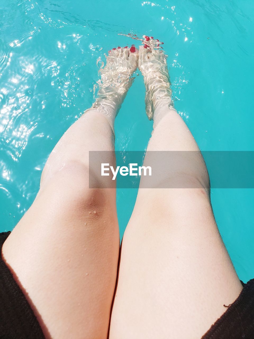 Low section of woman relaxing in swimming pool