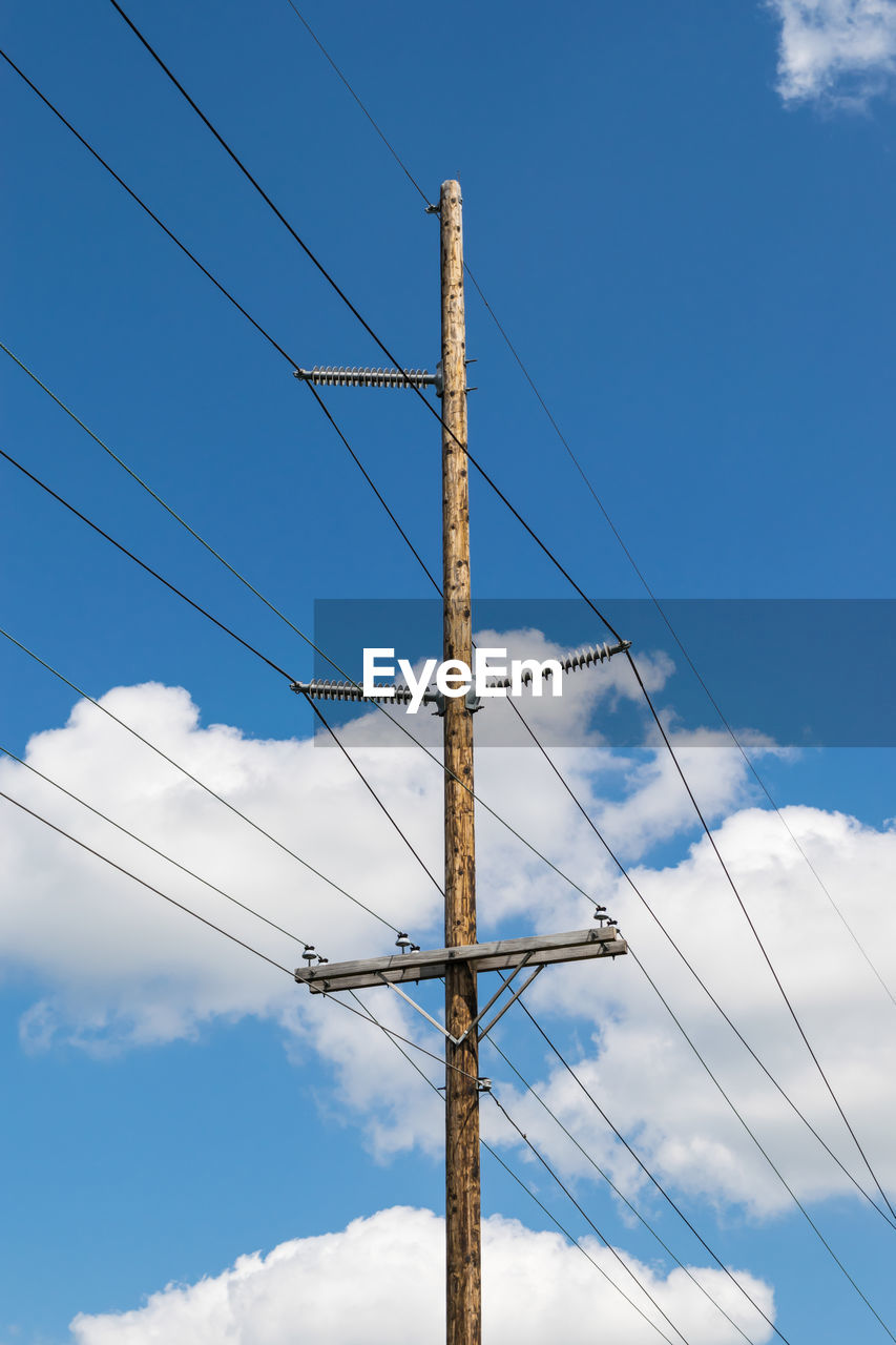Telephone pole, electric pole against a white cloud and blue sky.